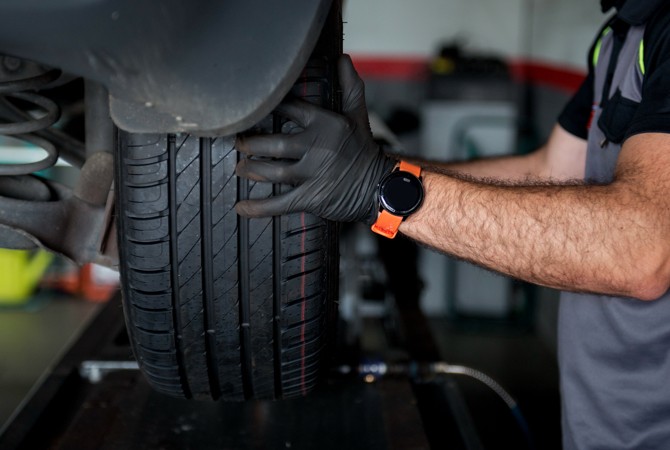 Auto Technician Inspecting Tire on Vehicle