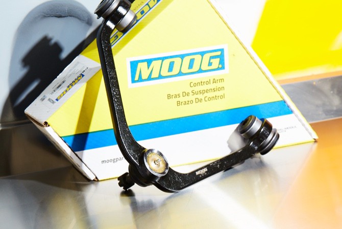 A MOOG control arm being presented infront of a MOOG control arm box