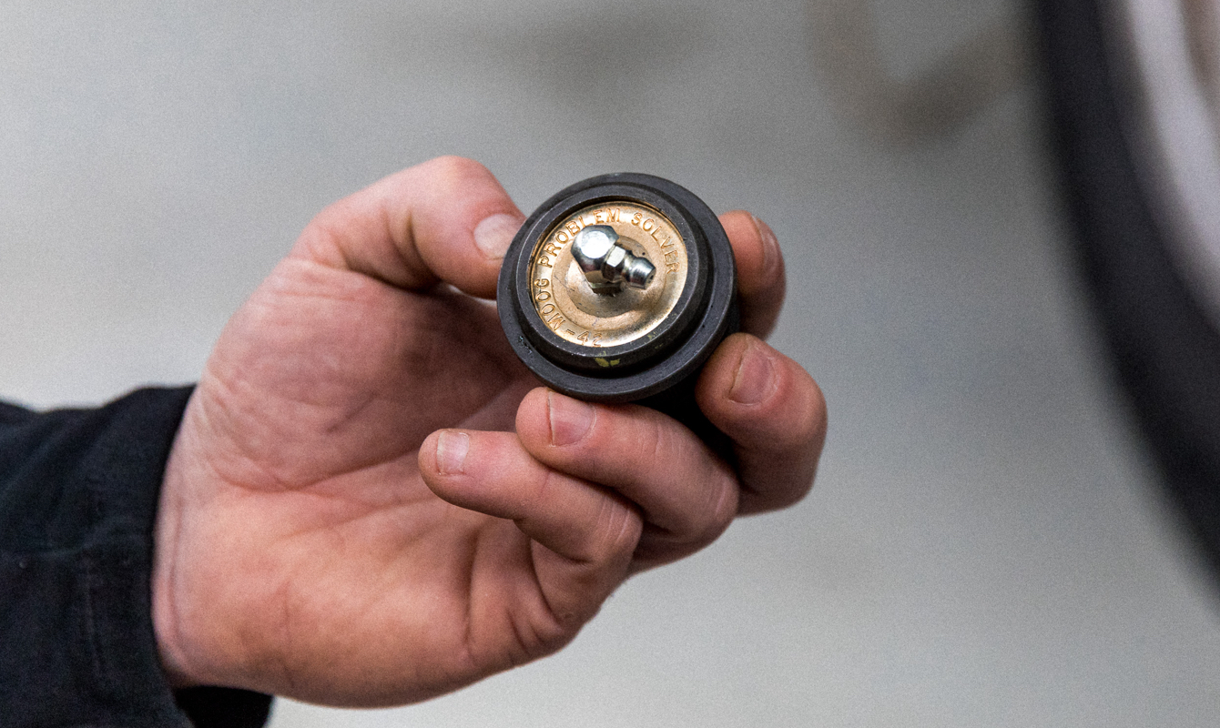 Worn out ball joints sitting on top of a vice in a mechanics bay